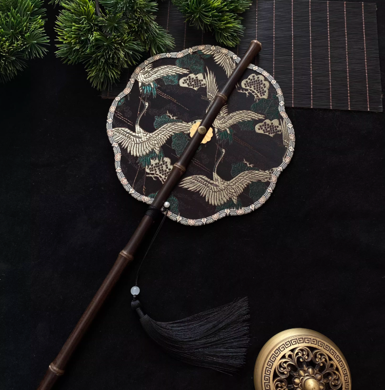 Éventail rond brodé noir et or – motif grues chinoises
