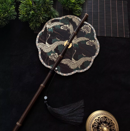 Éventail rond brodé noir et or – motif grues chinoises